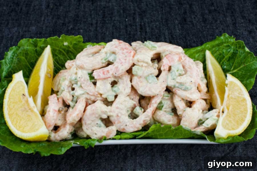 A beautifully plated shrimp salad on a bed of fresh lettuce, garnished with bright lemon wedges, ready to serve.