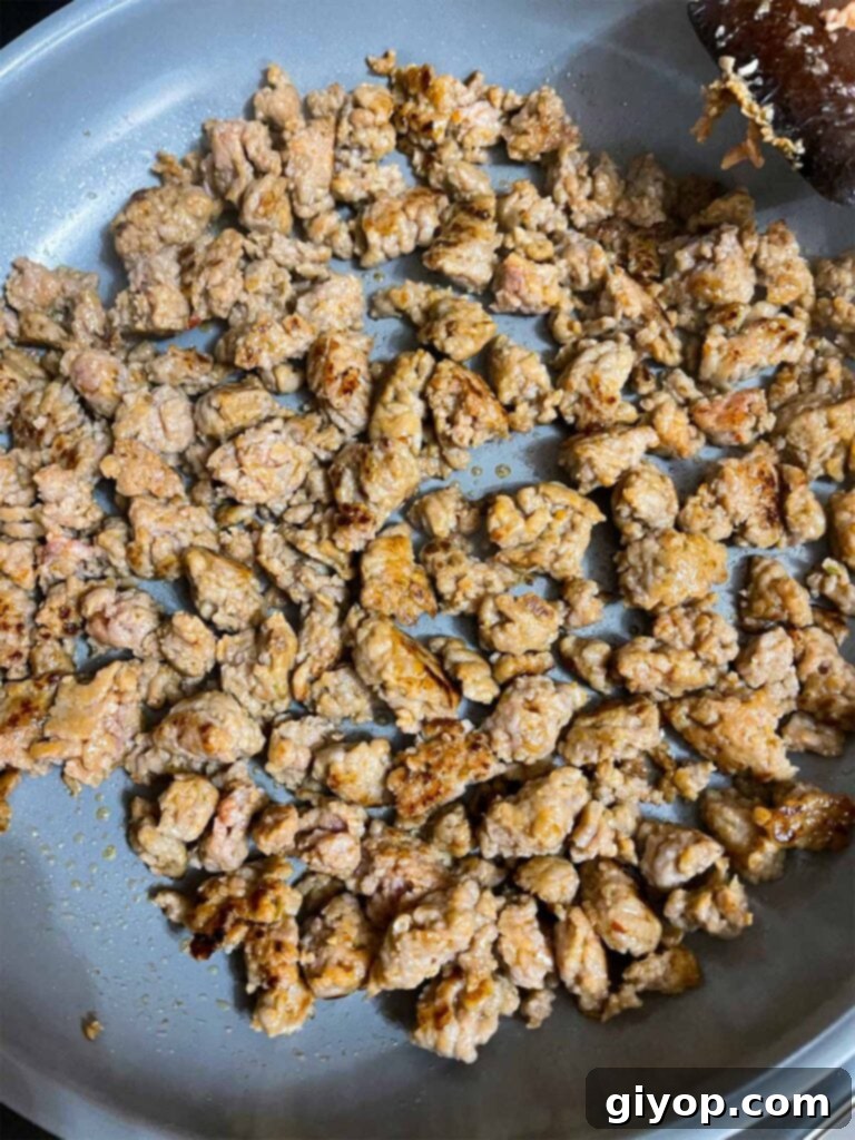 Ultimate Oven-Baked Spaghetti Delight 5 Italian sausage browning in a skillet, broken into pieces, ready to be drained.