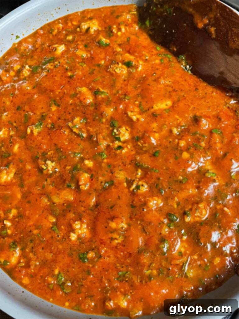 Ultimate Oven-Baked Spaghetti Delight 7 Marinara sauce with Italian sausage, onions, and herbs simmering in a large skillet for baked spaghetti.