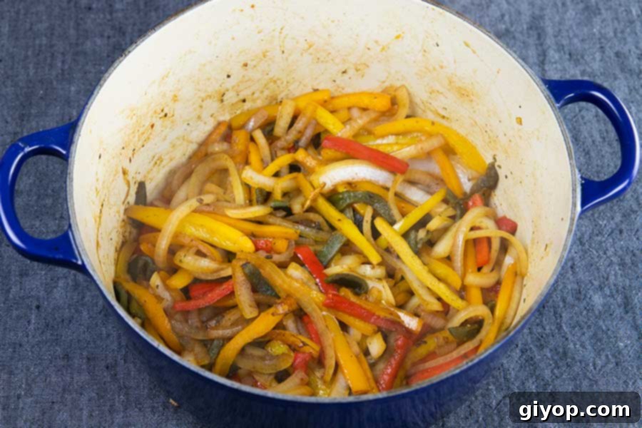 Delicious Gluten Free Chicken Fajita Stew 5 Caramelized bell peppers and onions simmering in a vibrant blue Dutch oven, forming the aromatic base for the chicken fajita stew.