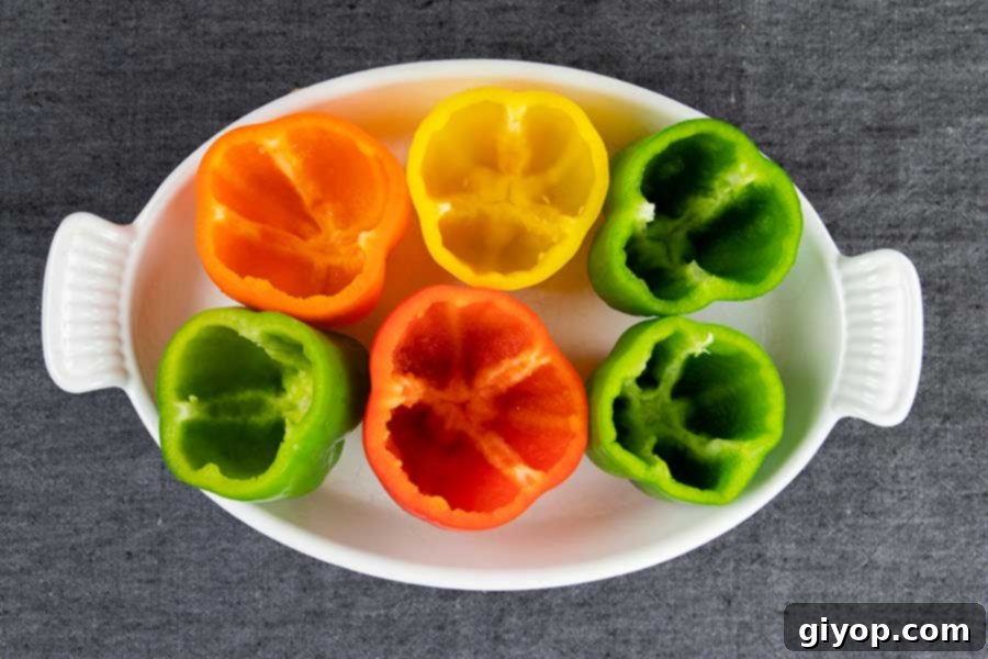 Colored raw bell peppers, tops removed and cored in a white baking dish