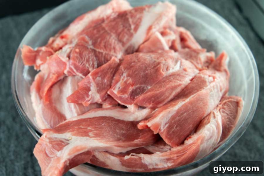 Strips of pork butt in a chilled glass bowl.