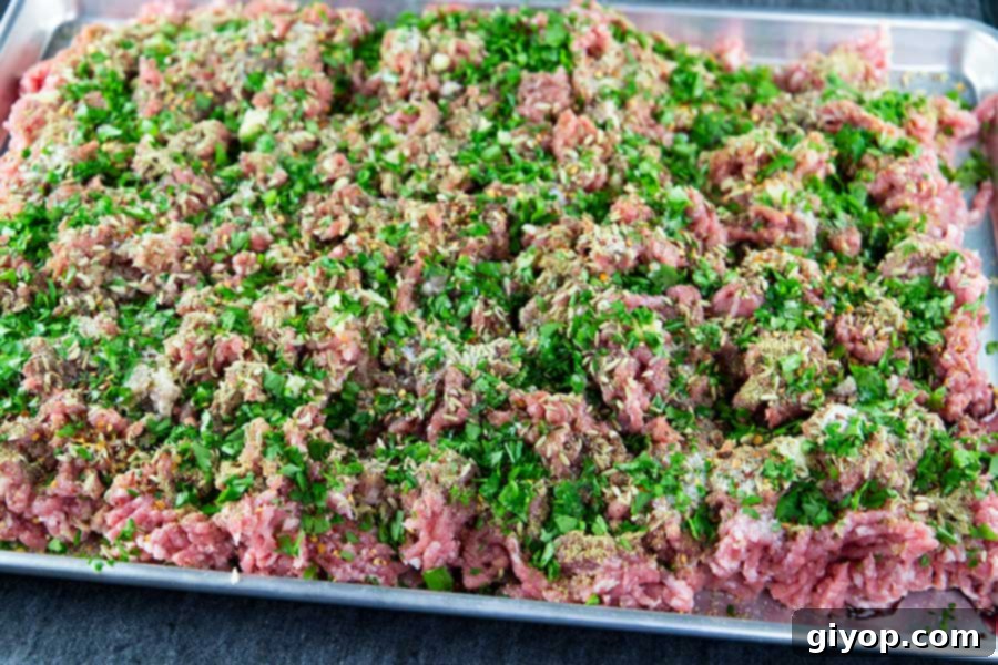 Ground pork sprinkled with the Italian sausage seasonings on a large baking sheet.