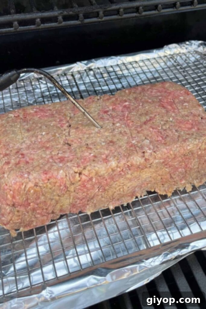 Slow-Smoked Meatloaf Masterpiece 9 uncooked meatloaf on the smoker with a temperature probe inserted.