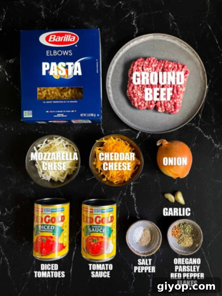 Comforting Homemade Cheesy Beefaroni 3 An array of fresh ingredients laid out, including ground beef, elbow pasta, onions, garlic, canned tomatoes, herbs, butter, and blocks of cheddar and mozzarella cheese.