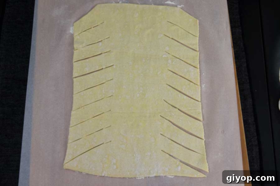 Raspberry Cream Cheese Swirl Danish 3 Puff pastry sheet laid out on parchment paper and carefully cut into strips, ready for filling and braiding.