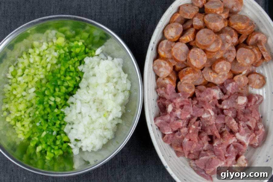 Diced celery, bell pepper, and onions in one bowl, and in another bowl is the diced pork and sausage.