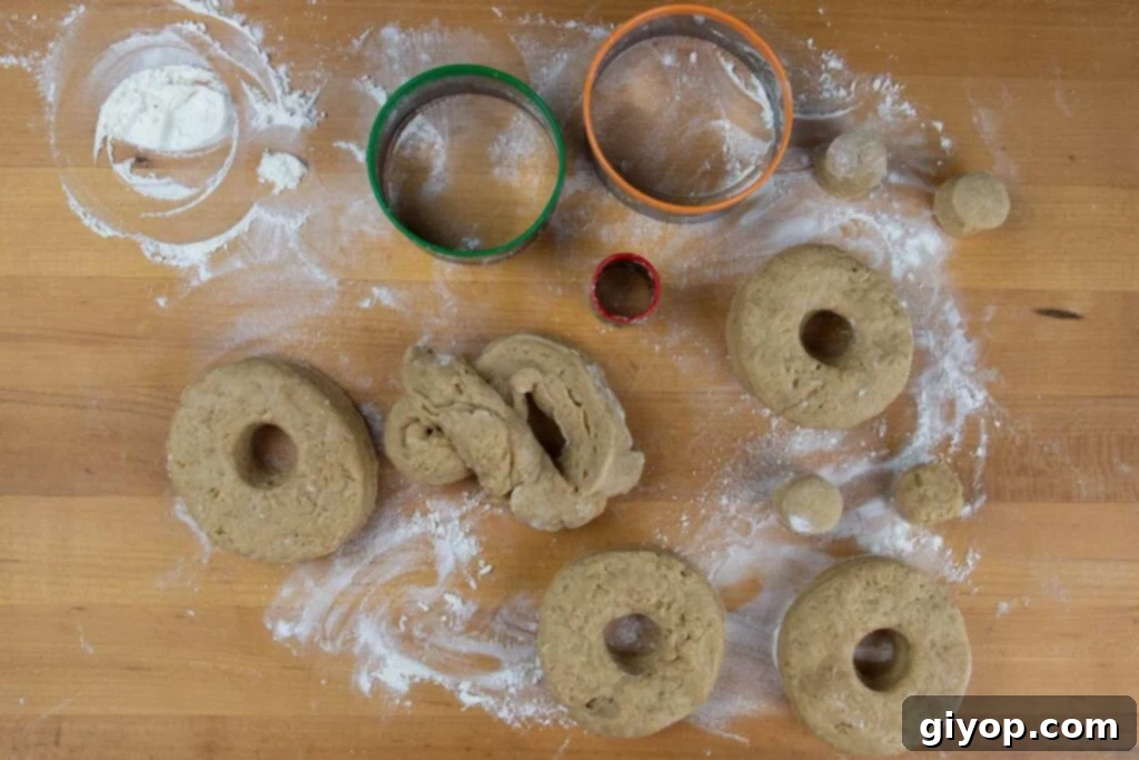 Ultimate Apple Cider Donuts Boiled Cider Edition 4 Cut out apple cider donut dough pieces arranged neatly on a wooden board, ready for frying.