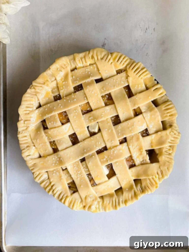 Unbaked lattice crust apple pie, brushed with egg wash and ready for baking on parchment paper.