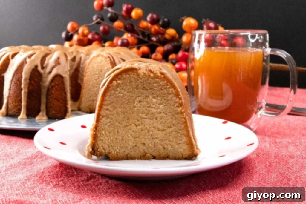 Cider-Glazed Apple Pound Cake 7 A delicate slice of apple cider pound cake on a white plate with subtle red polka dots, inviting a taste.