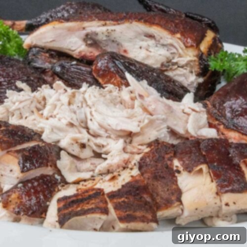Smoked chicken cut up on a white platter garnished with whole parsley.