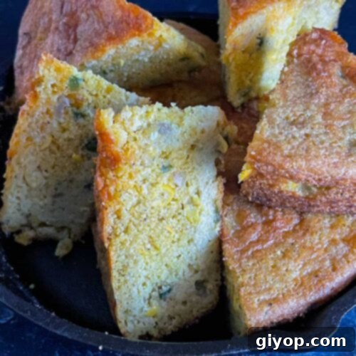 Creole cornbread slices stacked in a cast iron skillet.