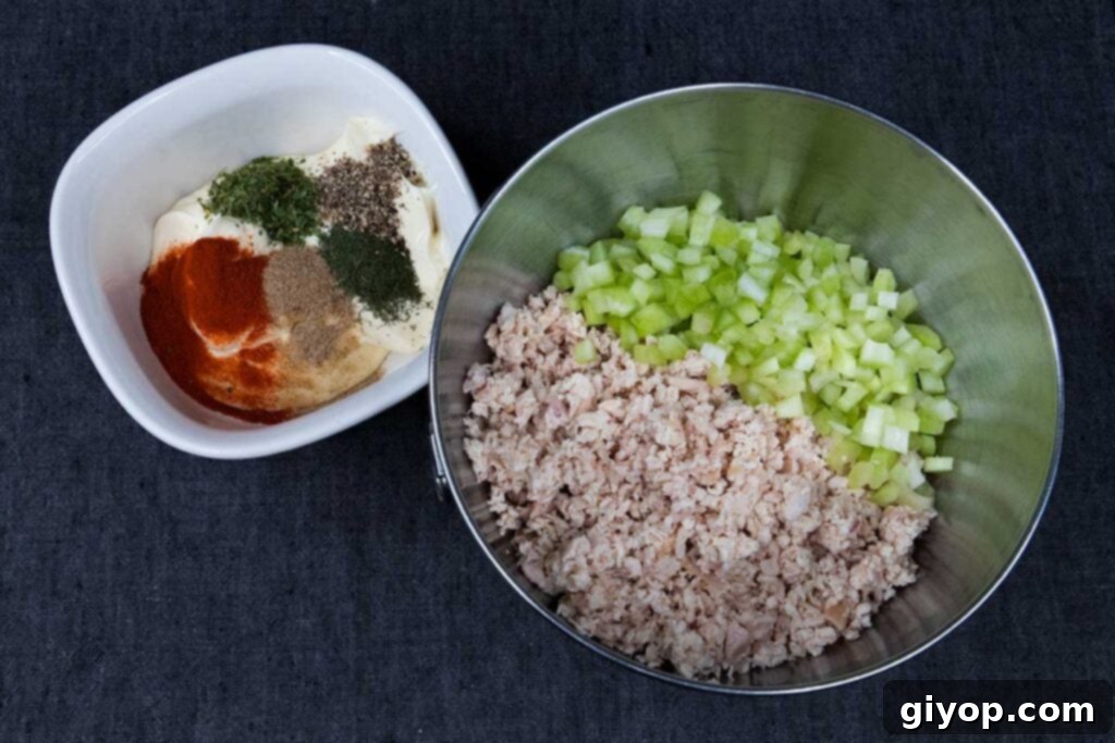 Minced smoked chicken and finely diced celery in a metal bowl, ready for mixing.