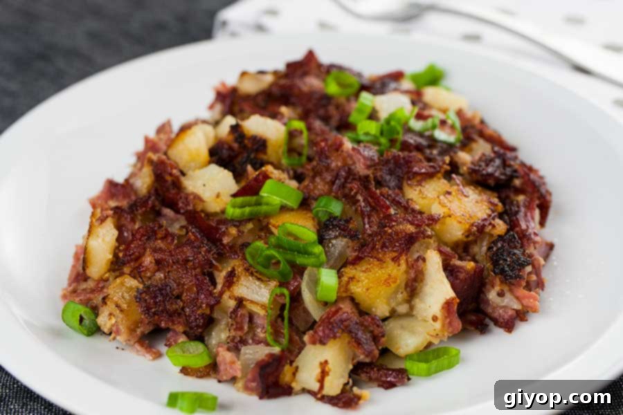 Crispy and flavorful Corned Beef Hash on a white plate, garnished with fresh green onions, ideal for a hearty St. Patrick's Day breakfast or brunch.