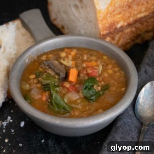 Slow cooker lentil soup with a loaf of bread.