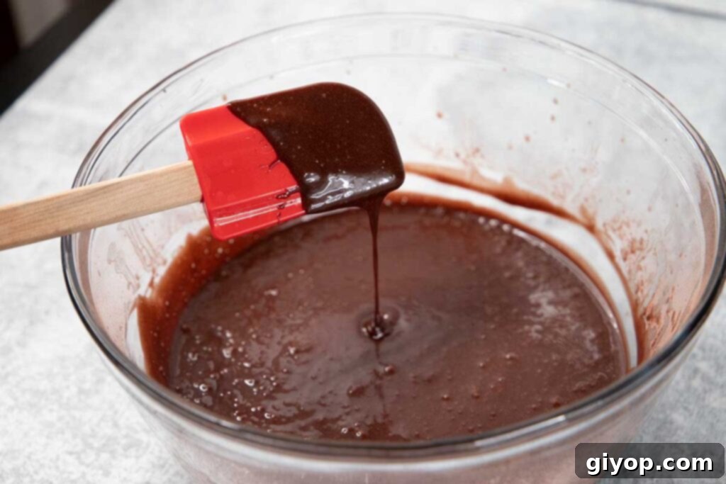 Decadent Chocolate Cupcakes 3 Rich, dark chocolate cupcake batter, perfectly smooth and ready for baking, swirled in a clear glass mixing bowl.