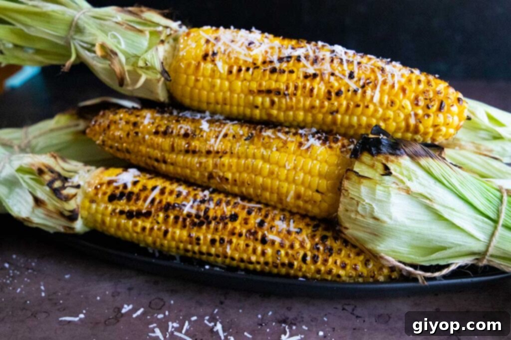 Grilled corn on the cob on a black plate.