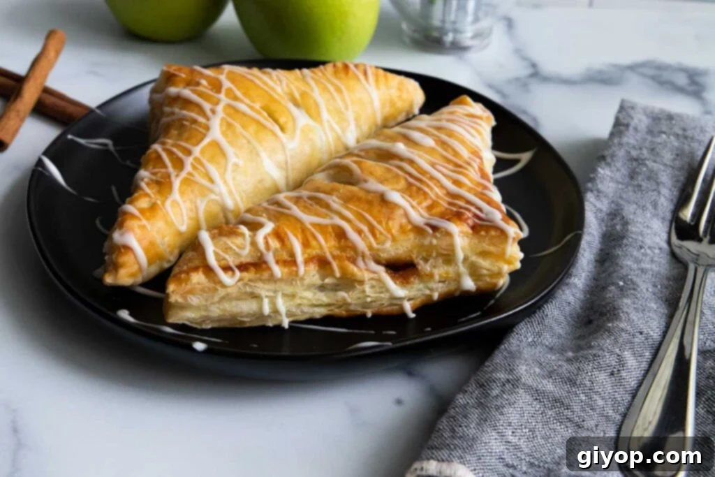 Puff pastry apple turnovers on a black plate.