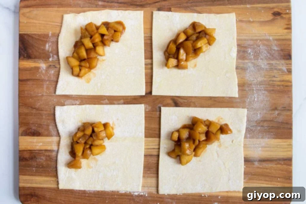 Puff pastry cut into squares with apple filling in the middle.