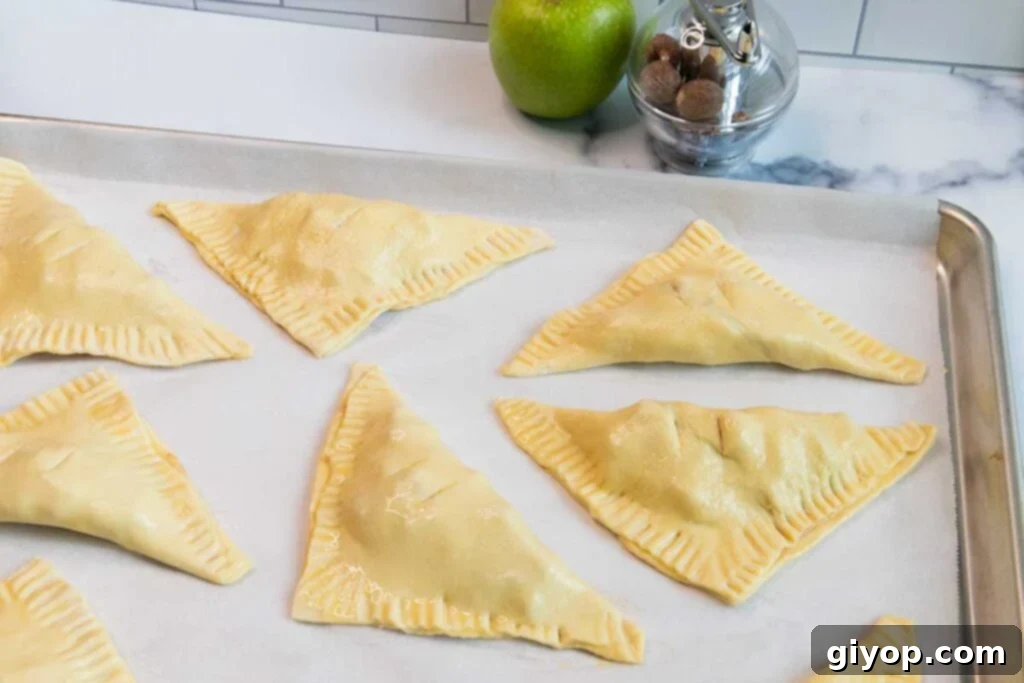 Formed apple turnovers on a baking sheet.