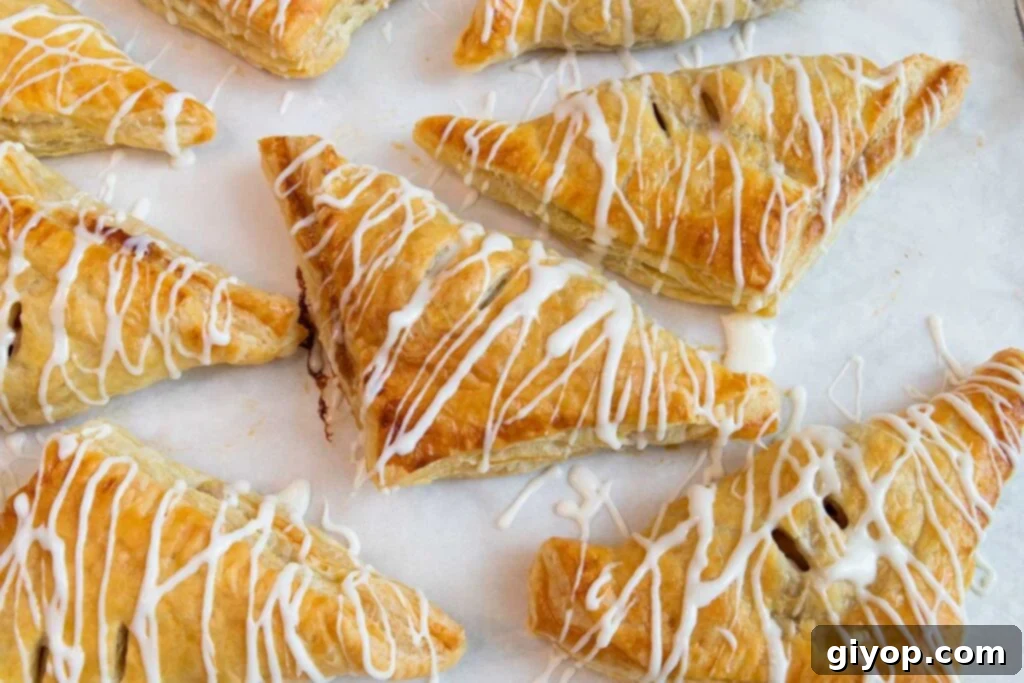 Glazed apple turnovers on a baking sheet.
