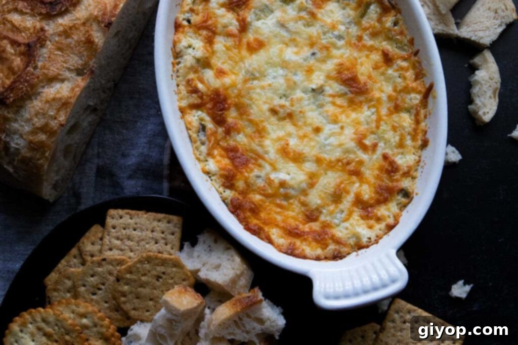 Close-up view of the rich, golden-brown baked artichoke dip in a white rectangular baking pan, showing its bubbly and cheesy texture.