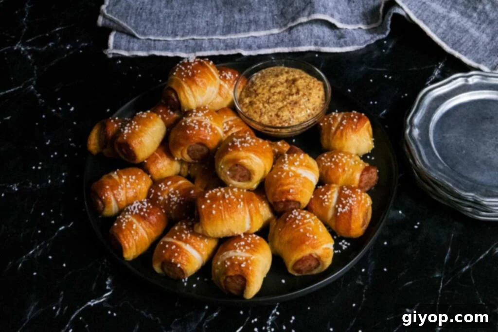 Freshly baked sausage pretzel bites arranged on a black plate with small bowls of dipping sauce.