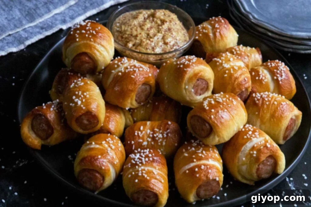 Sausage pretzel bites on a black plate with stone ground mustard garnish, presented as a delectable appetizer.