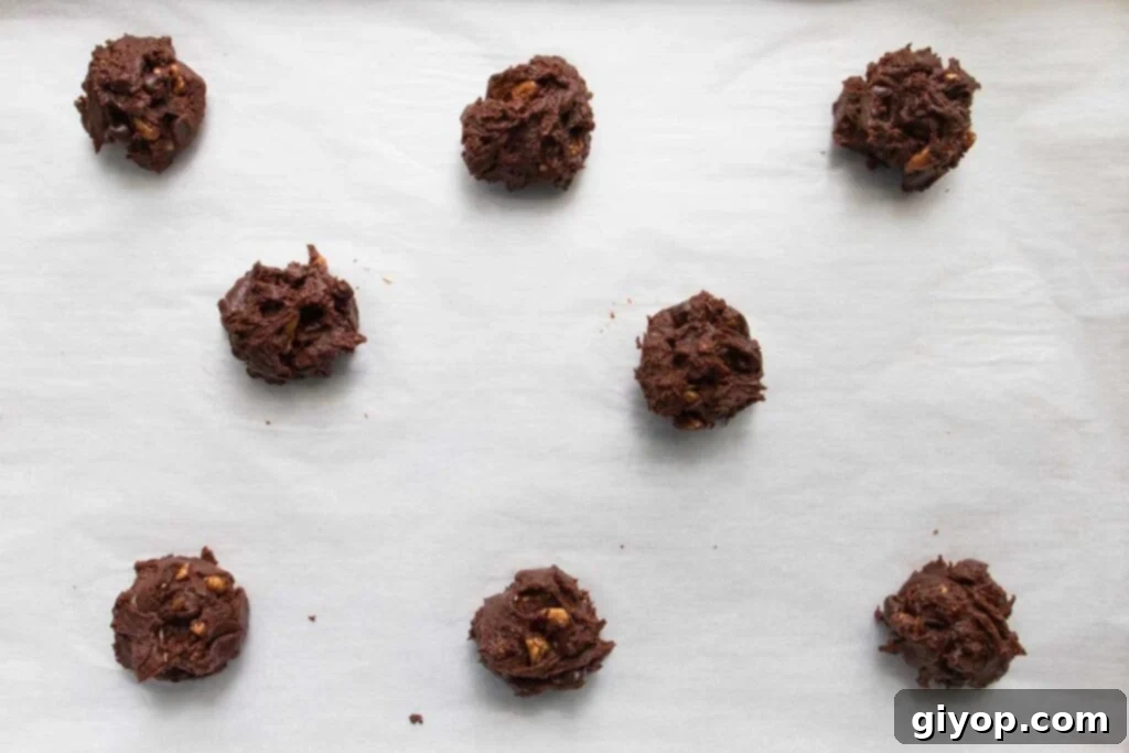 Fudgy Brownie Cookies 5 Brownie cookie dough balls precisely spaced on a parchment-lined baking sheet, ready for the oven.
