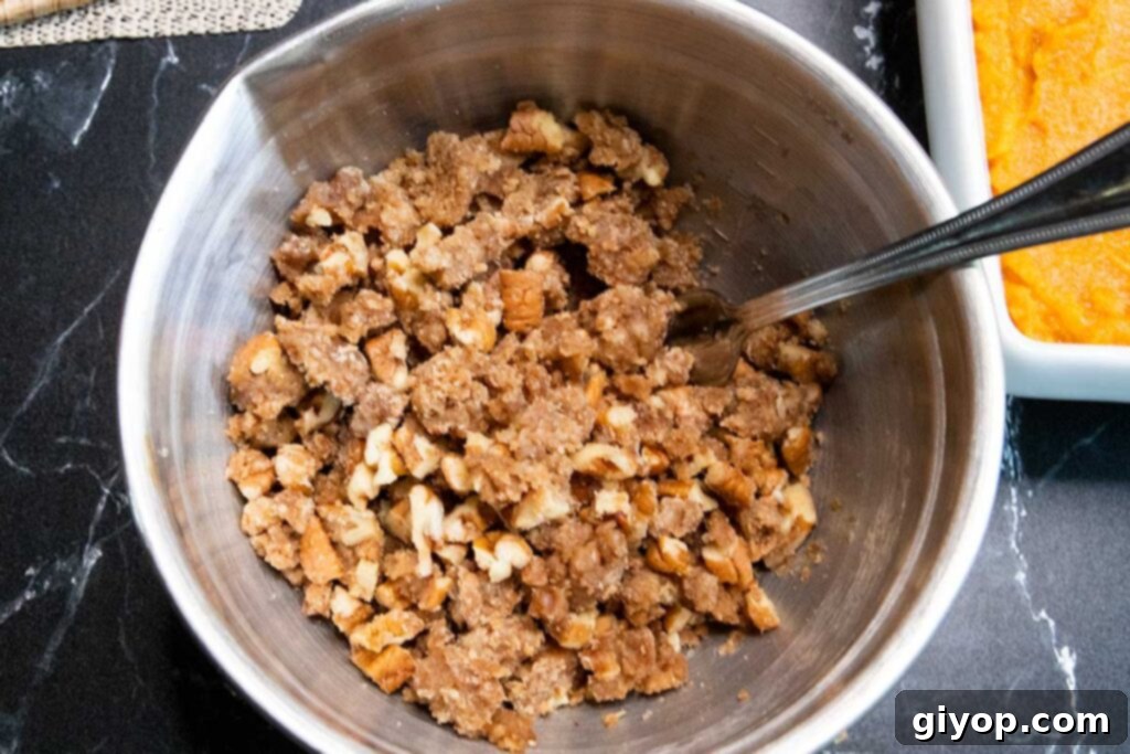 Buttery pecan crumb topping mixture in a metal mixing bowl, ready for use.