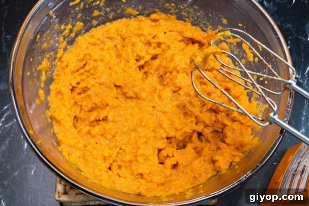 Creamy mashed sweet potatoes in a large glass mixing bowl.