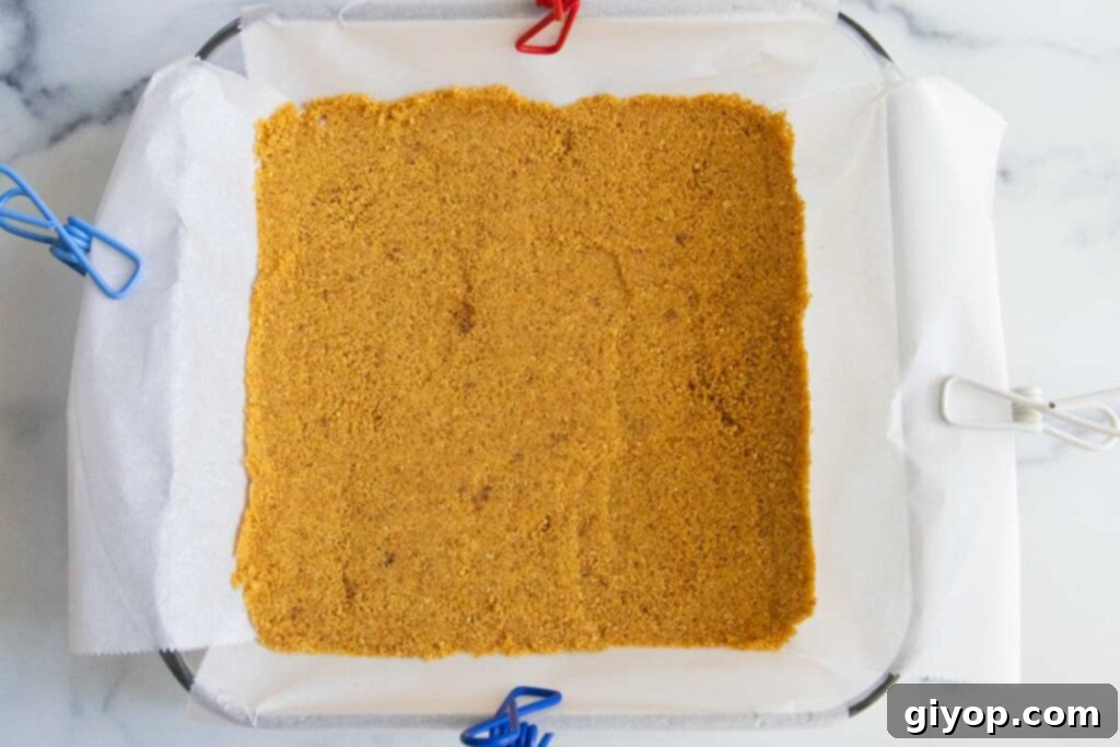 A simple graham cracker crust, evenly pressed into an 8x8 inch baking dish, ready for baking.