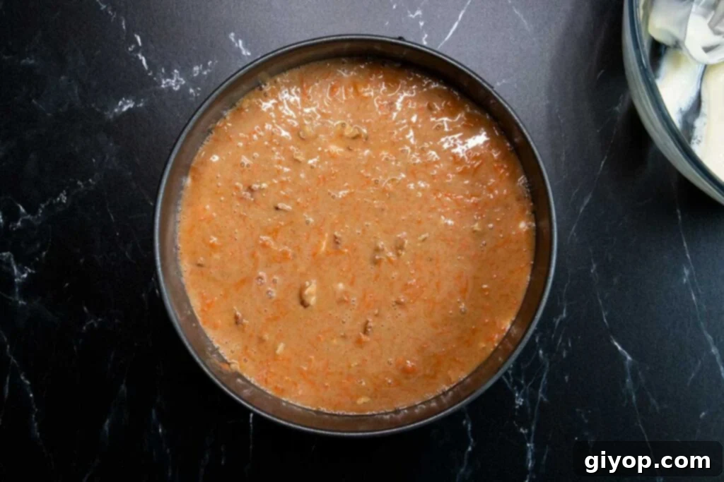 The third layer of carrot cake batter carefully spooned over the cheesecake.