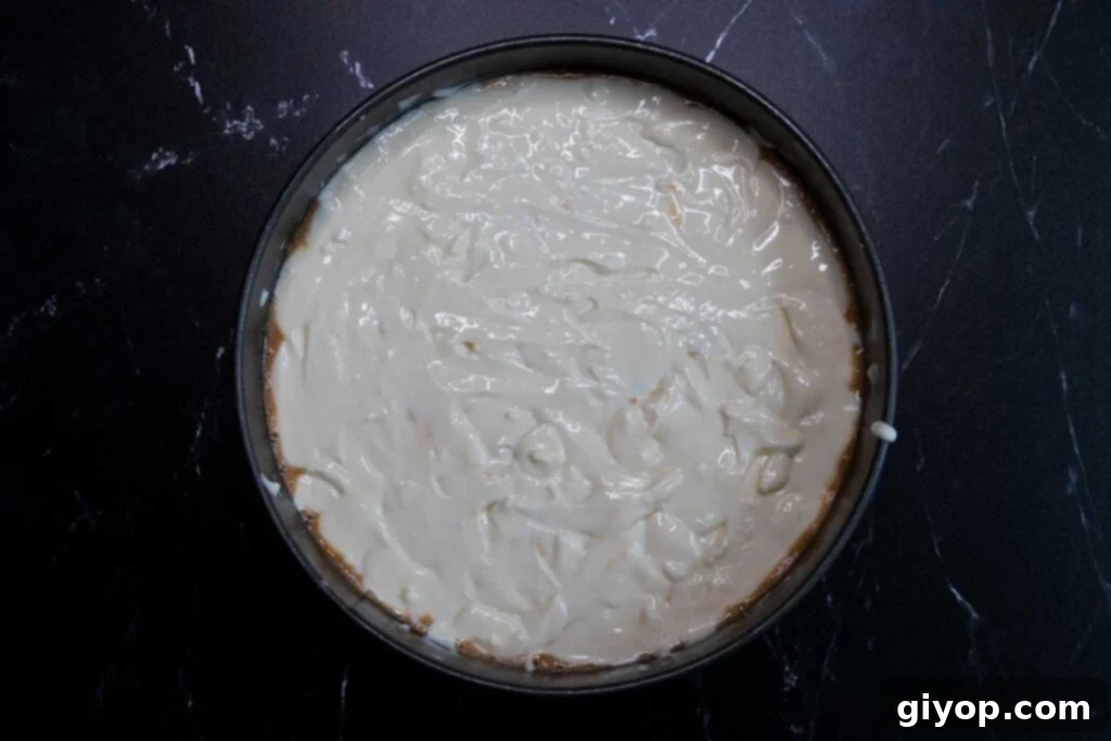The final layer of cheesecake batter covering the carrot cake layer.