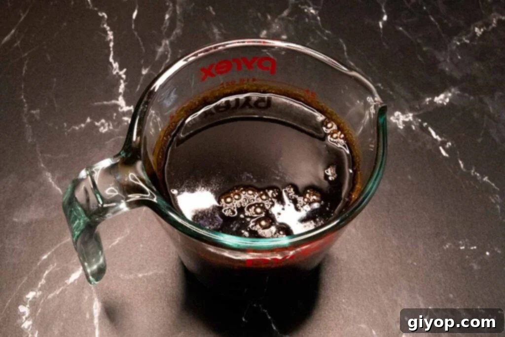 Boiled stout and molasses in a glass measuring cup, showing the dark, rich liquid.