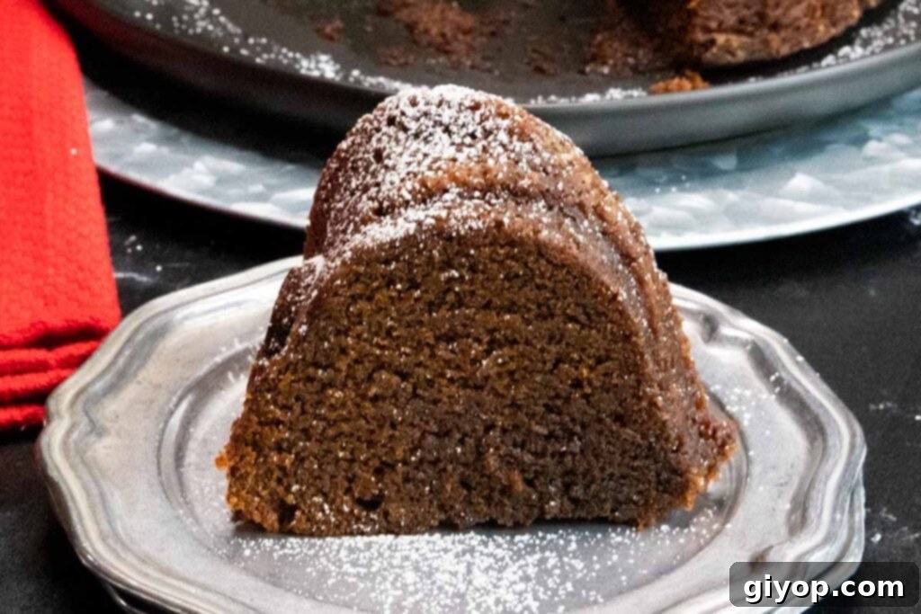 A beautiful slice of Gramercy Tavern gingerbread resting on a silver plate, artfully garnished with a snowy layer of powdered sugar.