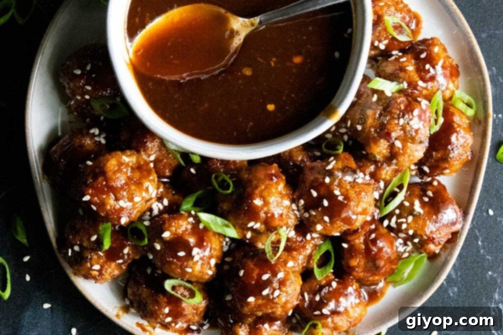 Irresistible Asian-inspired meatballs with a glossy, sweet and spicy sauce, garnished with fresh green onions and sesame seeds, ready to be served.