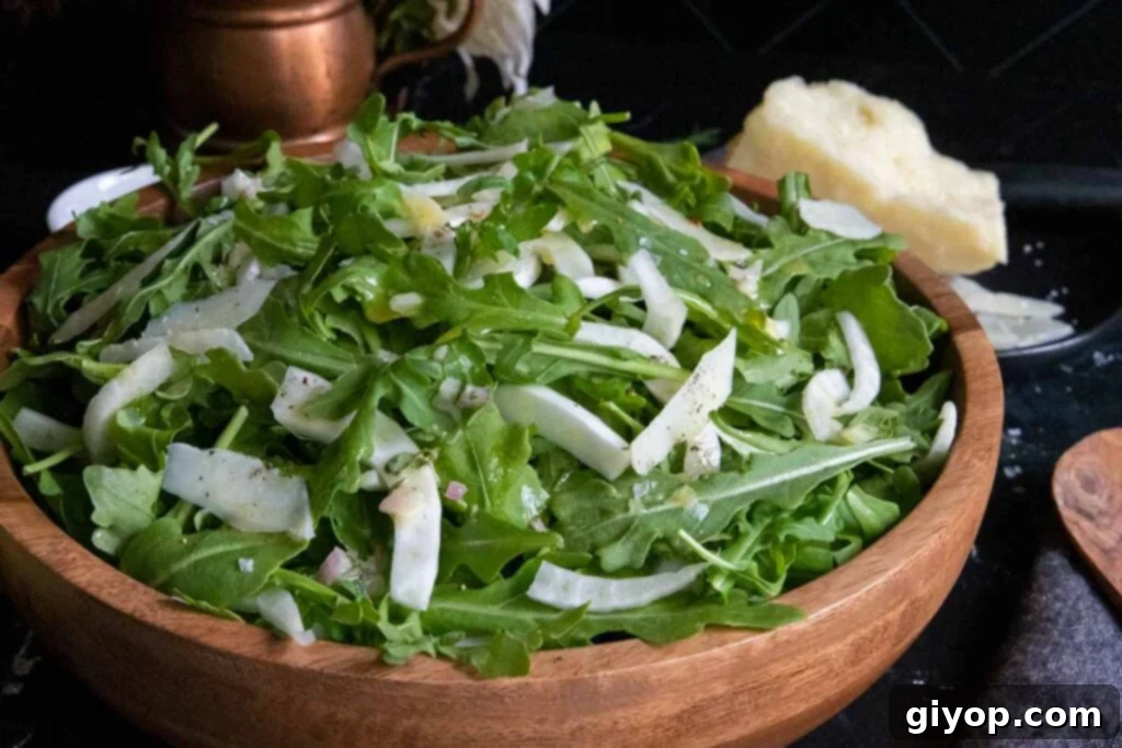 Zesty Arugula Fennel Medley 2 A vibrant arugula fennel salad generously piled in a rustic wooden bowl, ready to be served.