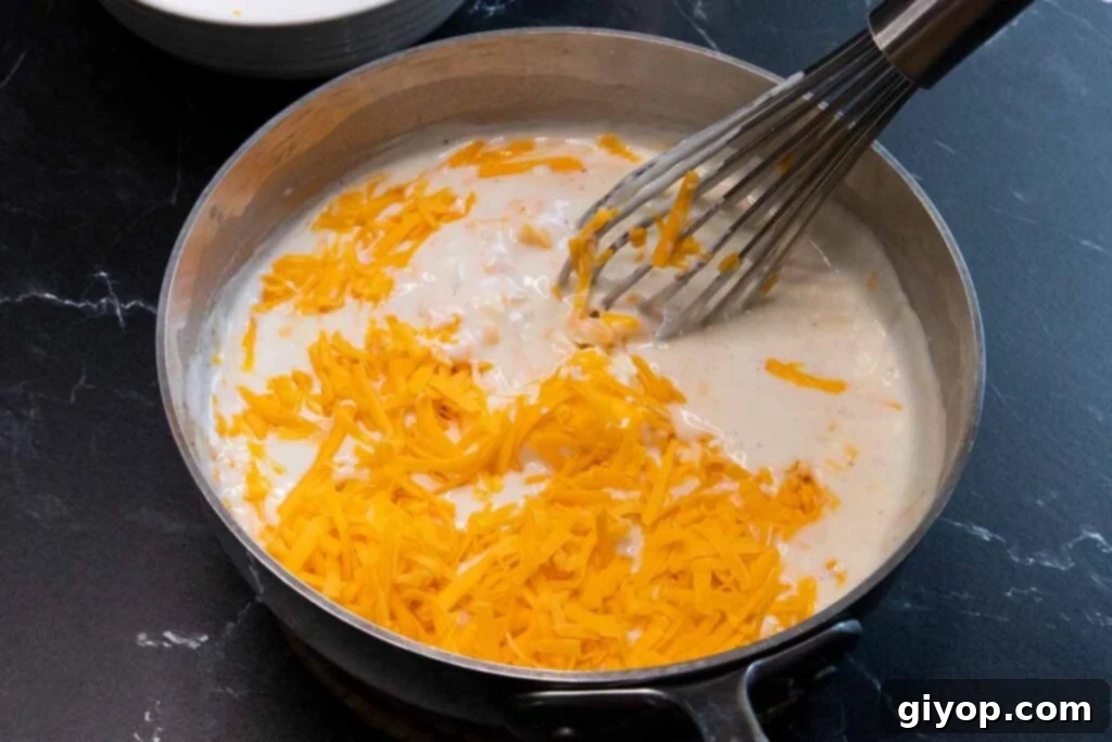 Creamy cheese sauce bubbling in a saucepan, showing its smooth consistency.