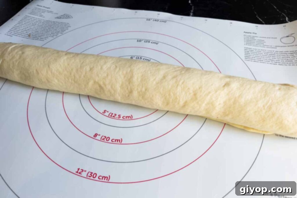 Maple bacon cinnamon roll dough, tightly rolled into a uniform log, ready to be cut into individual rolls.