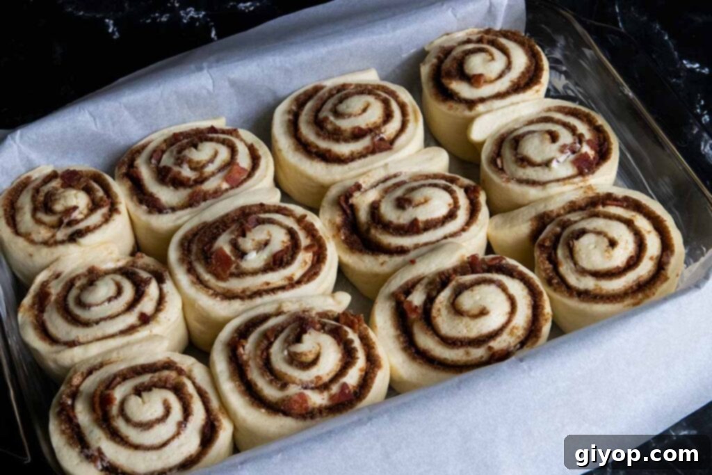 Proofed maple bacon cinnamon rolls, their sides touching, ready to be baked in the oven.