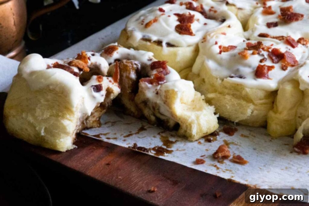 A freshly cut maple bacon cinnamon roll, revealing its tender, spiraled interior and abundant filling.