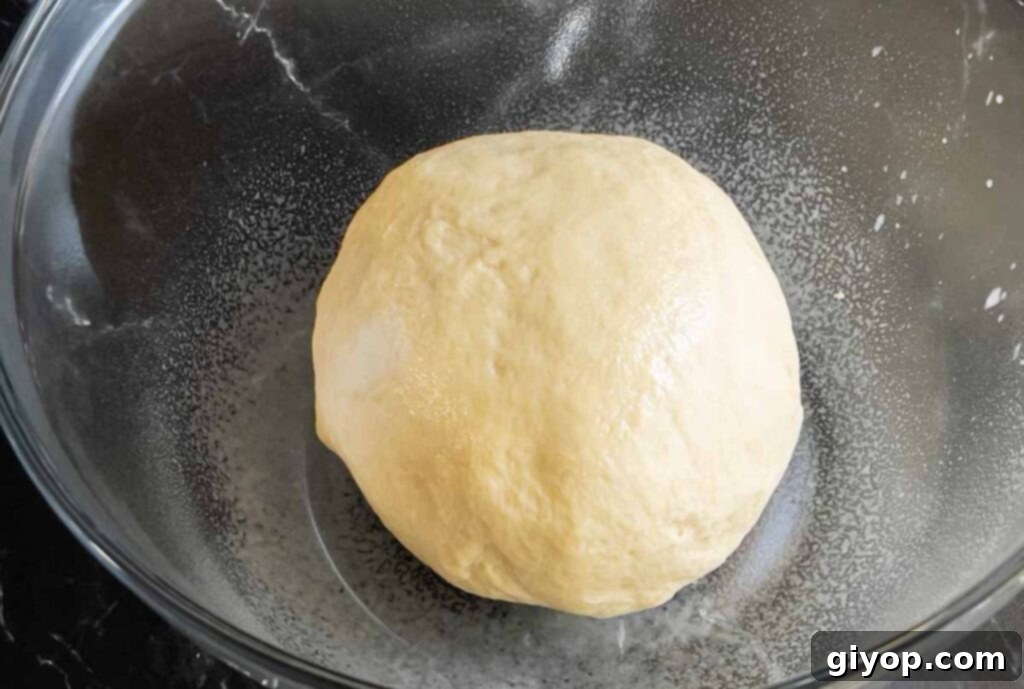Smooth and pliable cinnamon roll dough in a glass bowl, ready for its first rise.