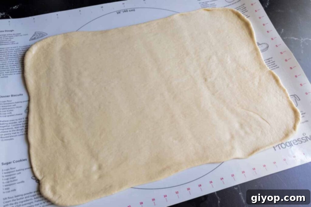 Cinnamon roll dough expertly shaped into a rectangular form on a lightly floured surface.