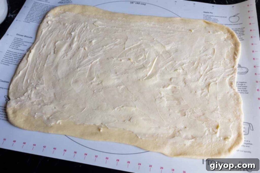 Rectangular cinnamon roll dough generously spread with room-temperature butter, ready for the filling.