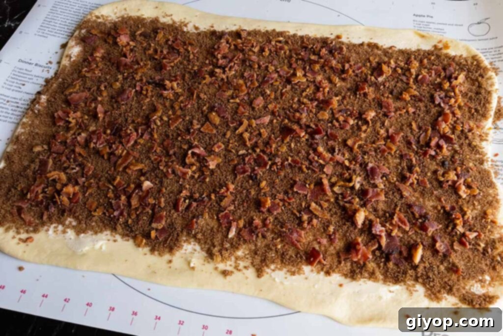 Cinnamon roll dough generously covered with brown sugar mixture and crispy bacon pieces.