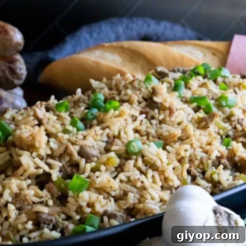 Crafting Perfect Cajun Dirty Rice 10 Cajun dirty rice in an oblong dish with a loaf of bread in the background.