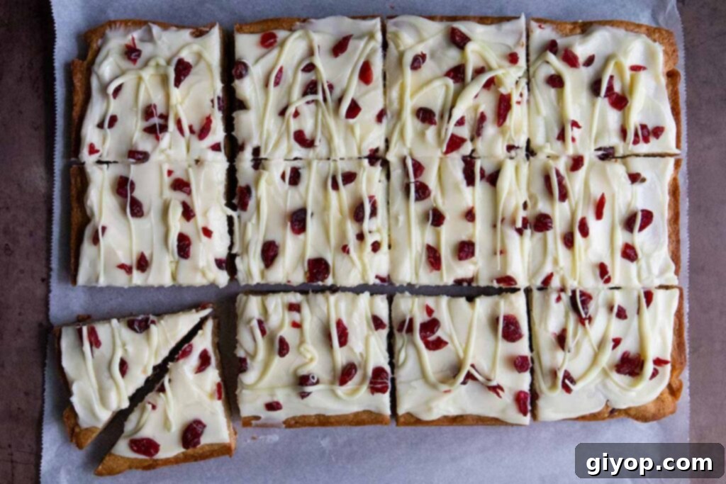 Perfectly sliced cranberry bliss bars, showing the signature triangle cuts, arranged on parchment paper.
