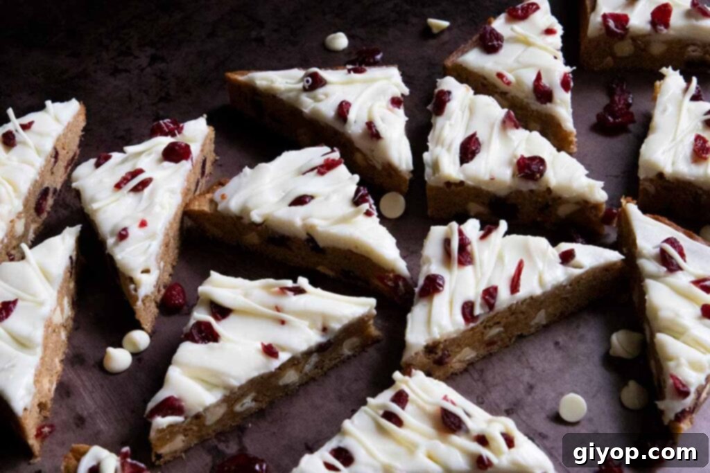 Numerous slices of cranberry bliss bars arranged on a sheet pan, ready to be enjoyed.
