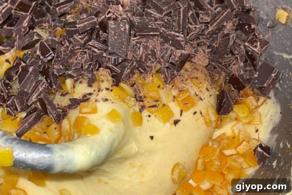 Decadent Chocolate Orange Panettone 7 Chocolate chunks and candied orange peel being added to the panettone dough in a mixer.